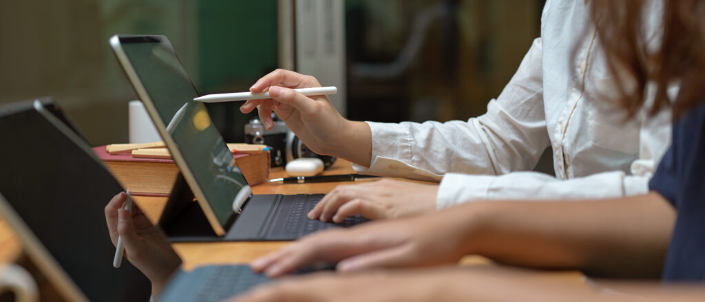 Side view of two workers consulting on their project while working with mock-up tablet on wooden table