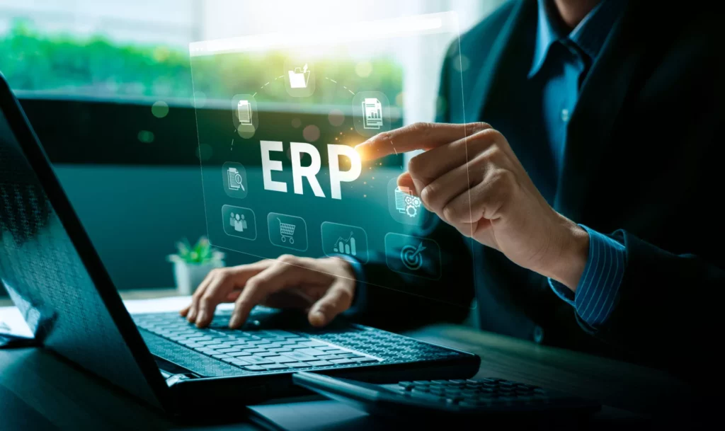 Person using a laptop and interacting with a transparent digital interface displaying “ERP” and icons representing business functions