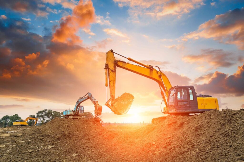 Excavators working at a construction site during sunset.