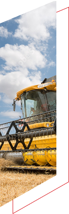 Yellow combine harvester in a field under clouds.