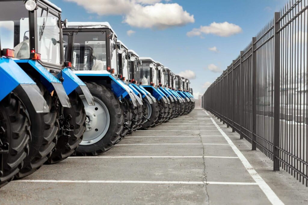 Row of blue tractors parked on pavement