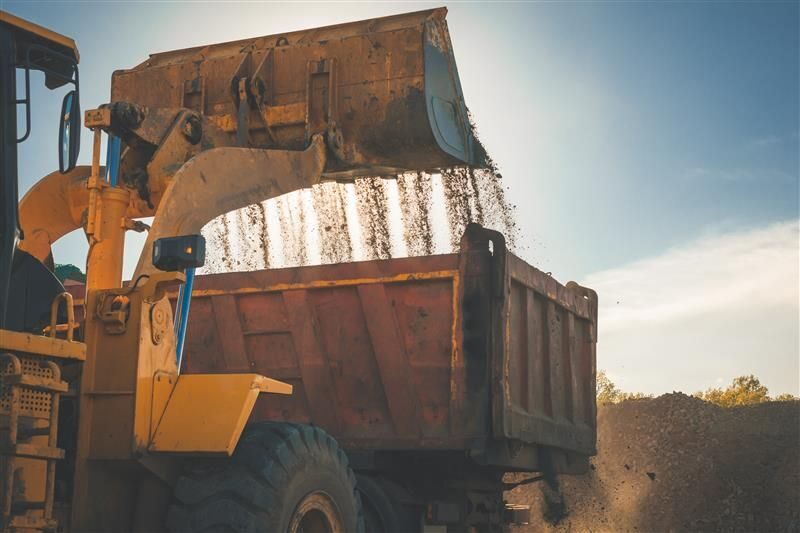 Excavator dumping dirt into a truck.