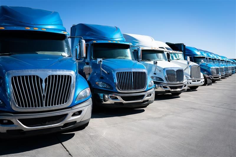 Row of blue freight trucks under clear sky