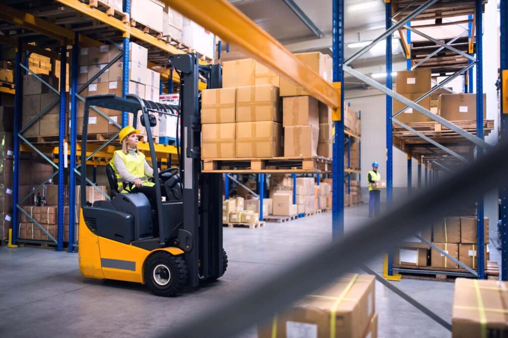 Warehouse worker operating a forklift with boxes.