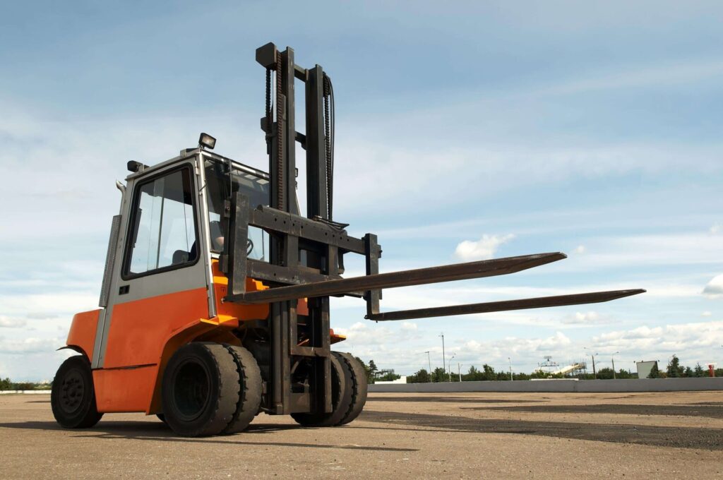 Orange forklift on an outdoor pavement.