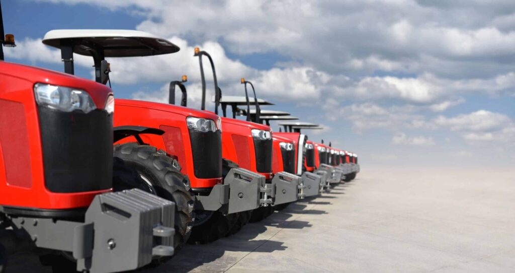 Row of red tractors against cloudy sky.
