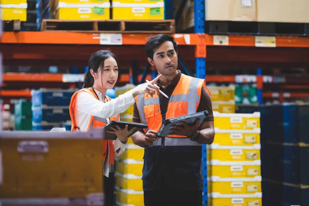 Two warehouse employees discussing with tablets