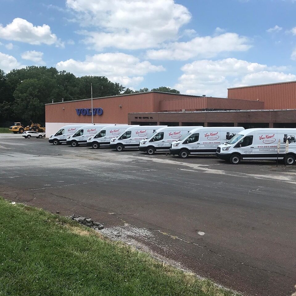 Row of delivery vans parked near a Volvo building.