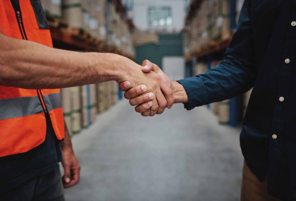 Two people shaking hands in a warehouse