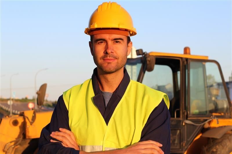 Construction worker in safety gear with machinery