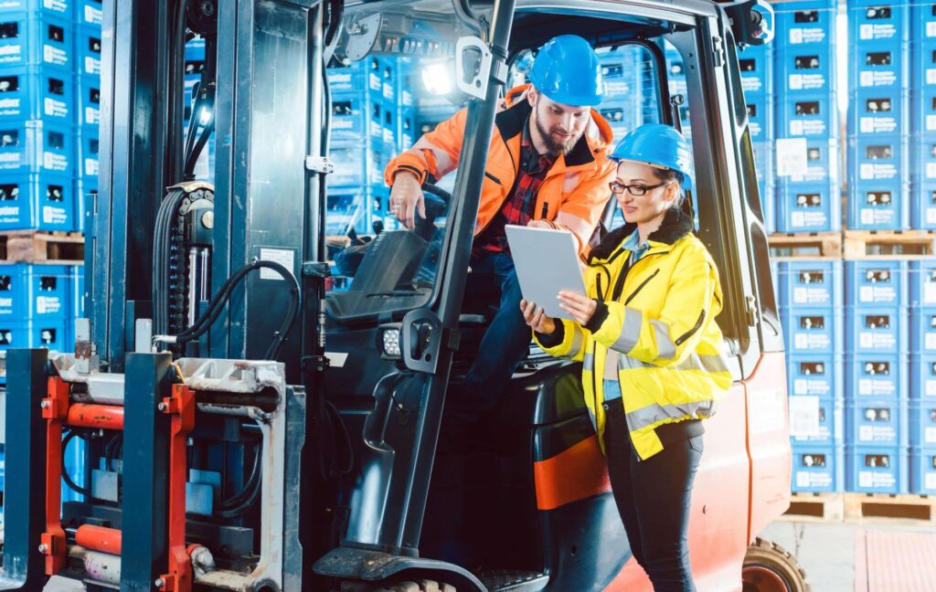 Warehouse workers using tablet with forklift.